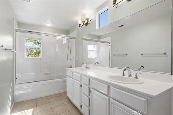 a bathroom with a sink double vanity granite tub shower and a mirror