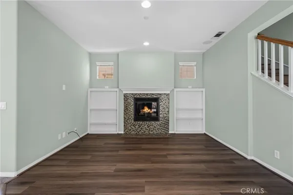 a view of an empty room with wooden floor and a fireplace