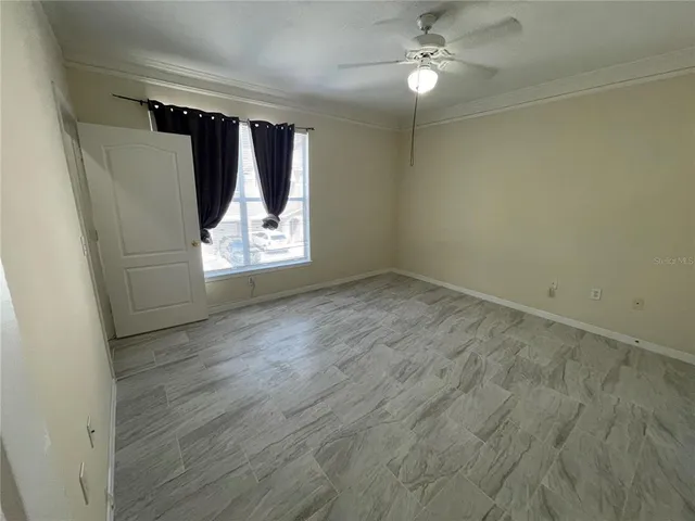 an empty room with wooden floor fan and windows