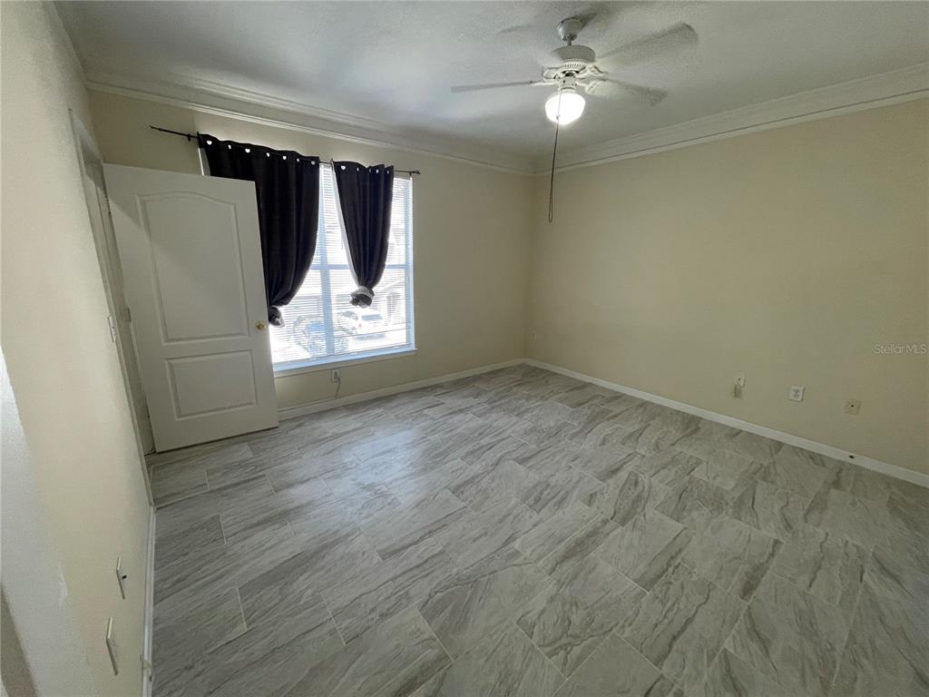 18108 Villa Creek Drive Tampa, FL 33647 - Photo 22 of 25 an empty room with wooden floor fan and windows