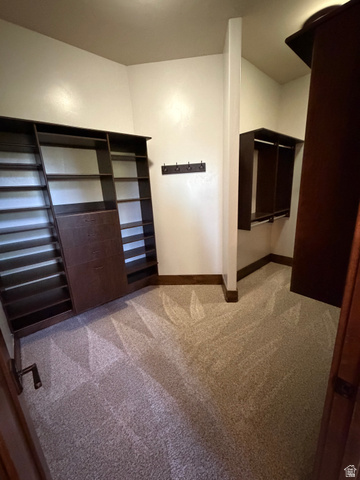 4536 North 475 East Provo, UT 84604 - Photo 42 of 65 Walk-in closet featuring built-in dark wood cabinetry, extensive shelving, integrated drawers, hanging rods, and neutral-toned carpeting