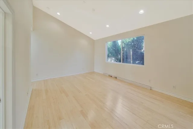 a view of an empty room with wooden floor and windows