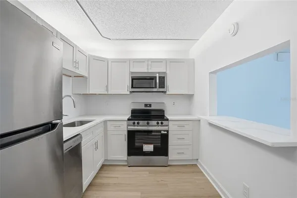a kitchen with stainless steel appliances granite countertop a stove top oven a sink and a microwave