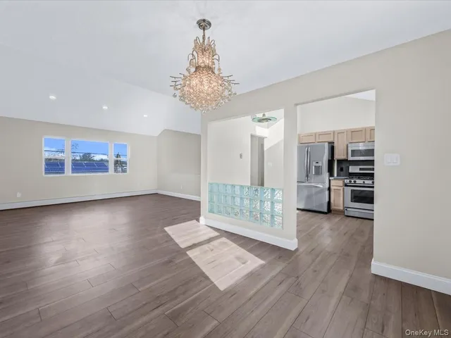 a view of a big room with wooden floor and windows