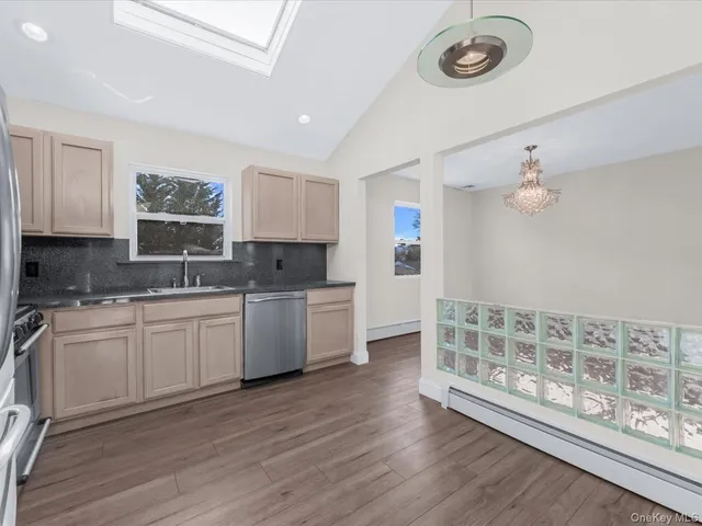 a kitchen with granite countertop a stove a sink and white cabinets with wooden floor