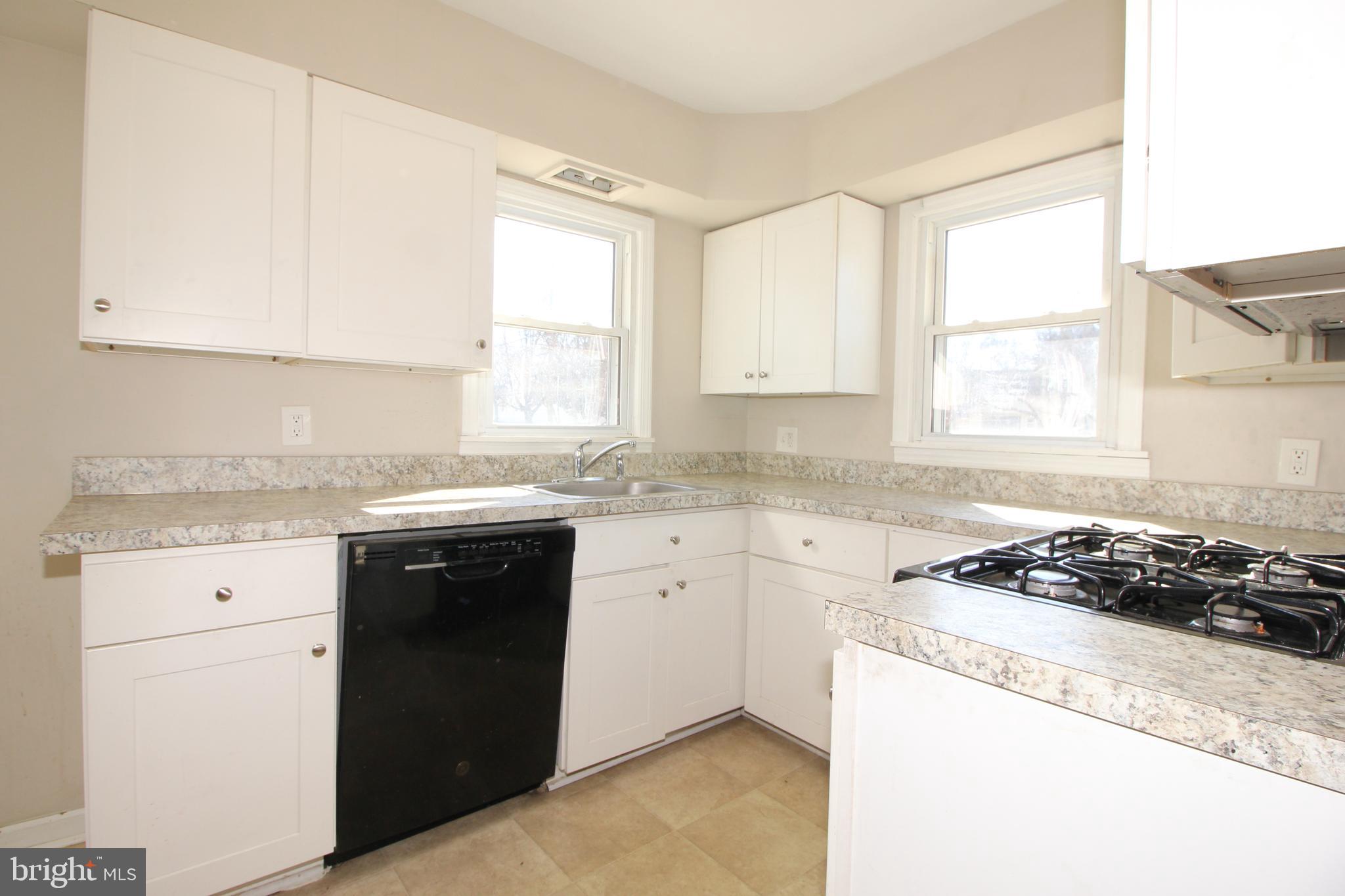 63 Ridgley Street Mount Holly, NJ 08060 - Photo 11 of 30 a kitchen with granite countertop a sink white cabinets and a window