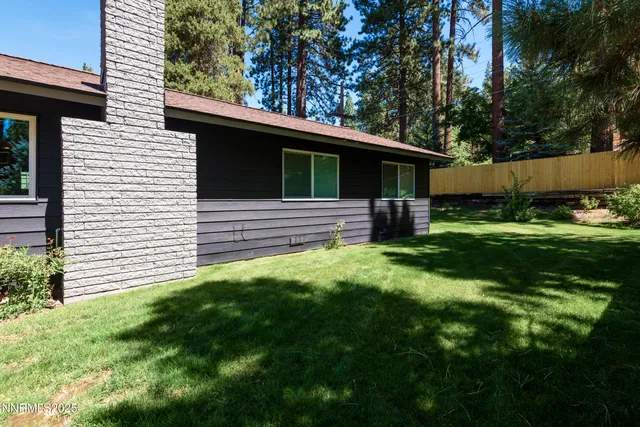 a backyard of a house with table and chairs under an umbrella