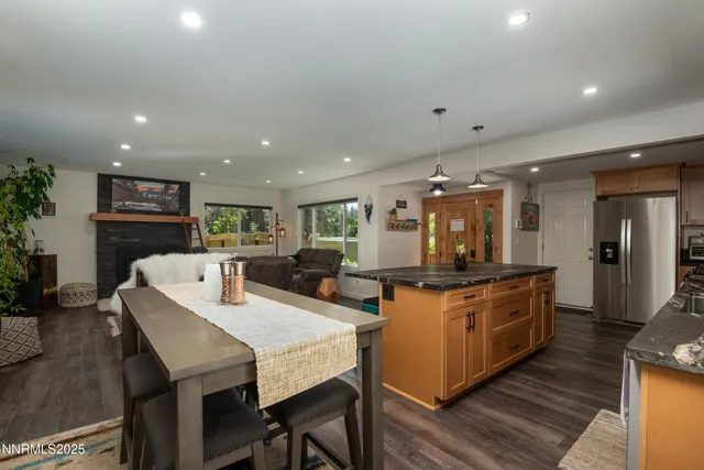 a kitchen with stainless steel appliances kitchen island granite countertop a stove a sink a refrigerator and a dining table with wooden floor