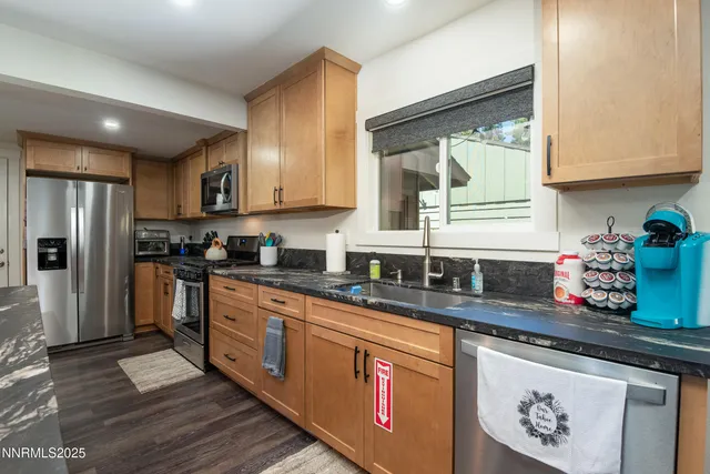 a kitchen with granite countertop a sink stainless steel appliances and cabinets