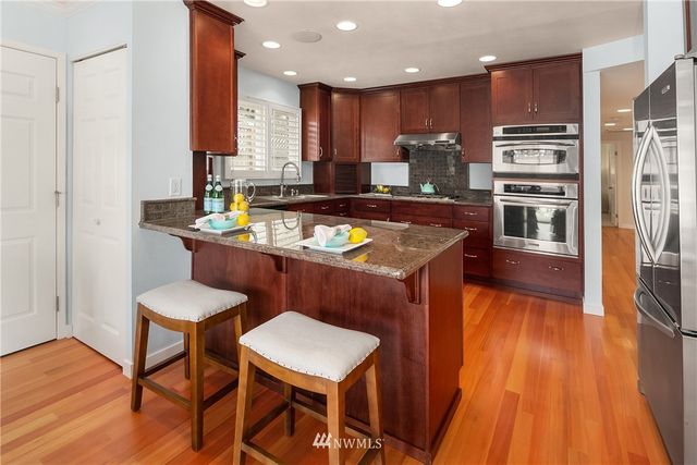 a kitchen with stainless steel appliances granite countertop a table chairs sink and wooden floor