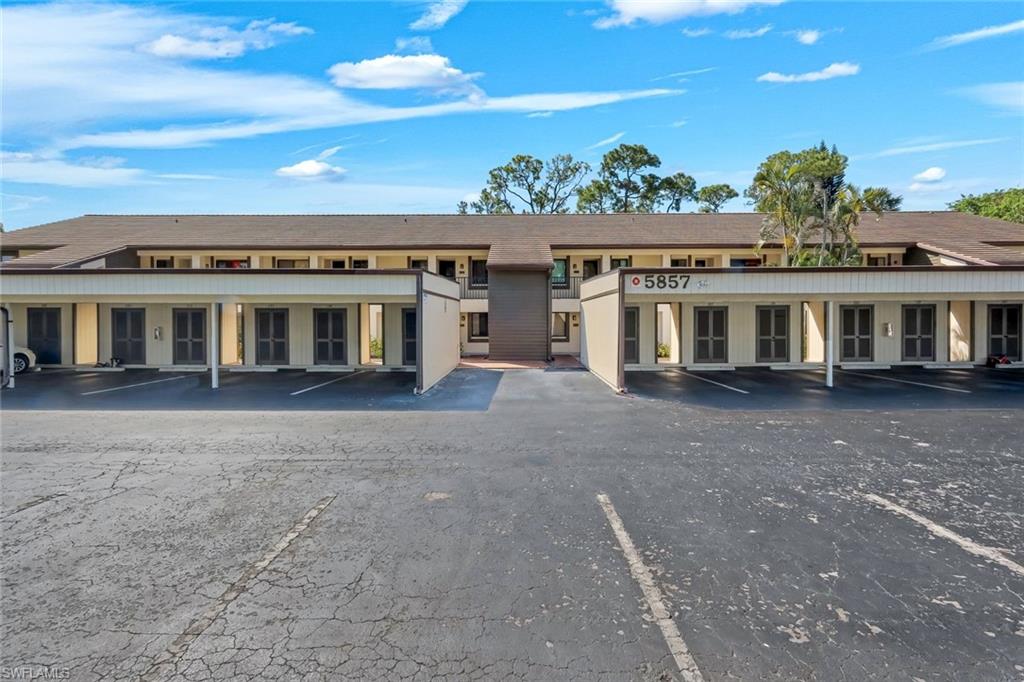 5857 Rattlesnake Hammock Road, Unit 101 Naples, FL 34113 - Photo 2 of 19 Multi-level condominium building featuring a brown shingle roof and covered parking spaces