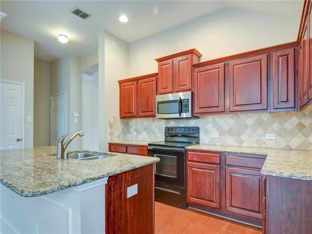 a kitchen with stainless steel appliances granite countertop a sink dishwasher stove and cabinets with wooden floor