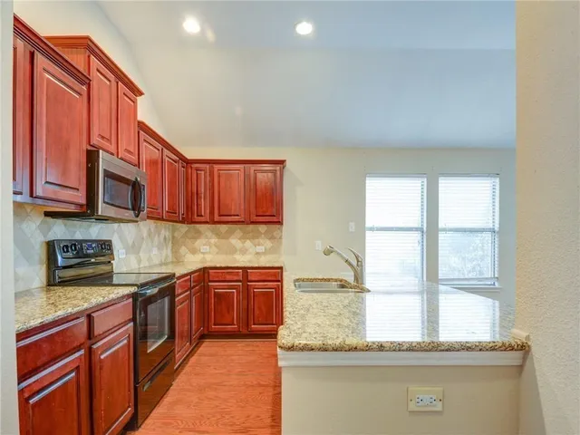 a kitchen with stainless steel appliances granite countertop a sink stove and cabinets