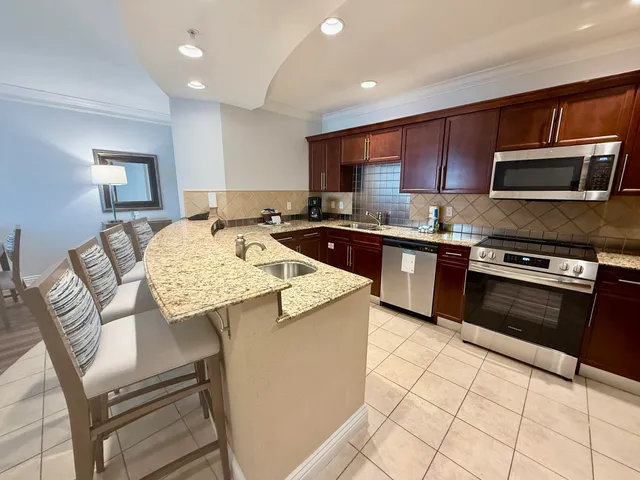 a kitchen with stainless steel appliances granite countertop a stove top oven a sink dishwasher and white cabinets