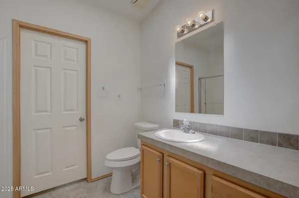 an empty room with chandelier fan and windows