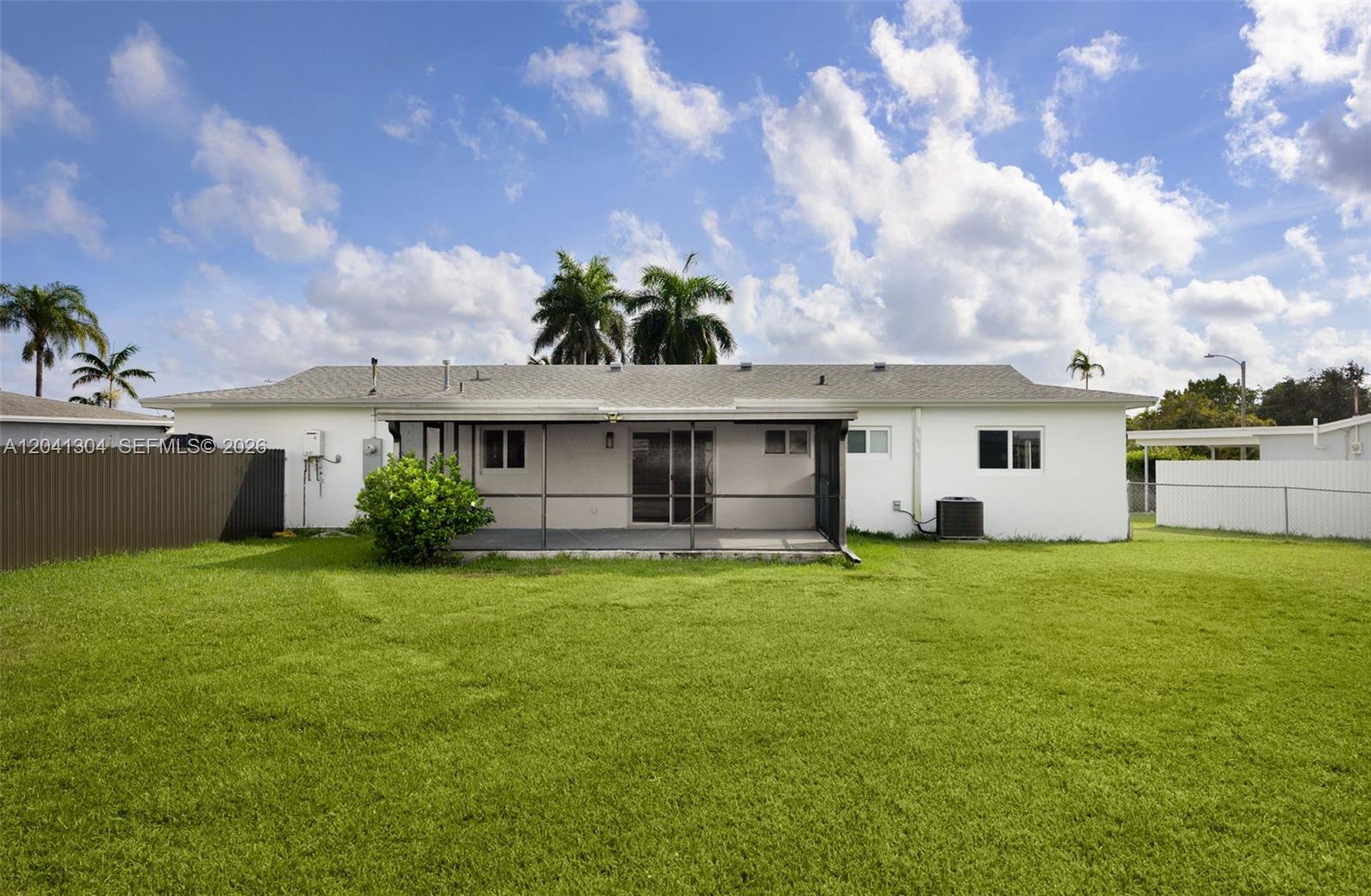 10340 Southwest 157th Street Miami, FL 33157 - Photo 19 of 24 Backyard & Rear Exterior – Large fenced backyard with plenty of open green space for recreation, gardening, or outdoor gatherings. The screened patio extends the home's indoor-outdoor living appeal.