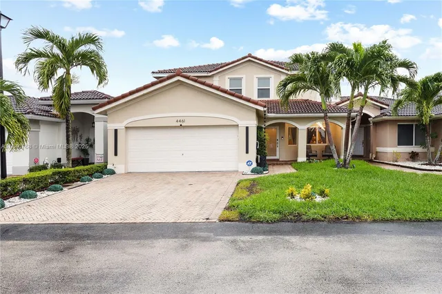 a front view of a house with a garden and palm tree