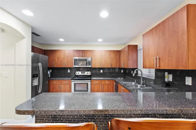 a kitchen with stainless steel appliances granite countertop a refrigerator a stove and a sink