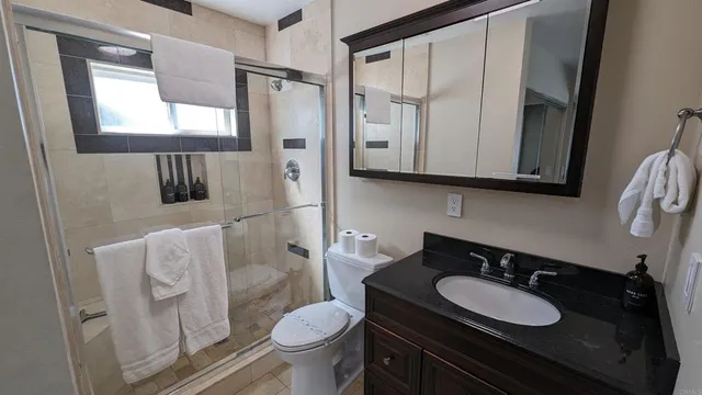 a bathroom with a granite countertop sink toilet and mirror