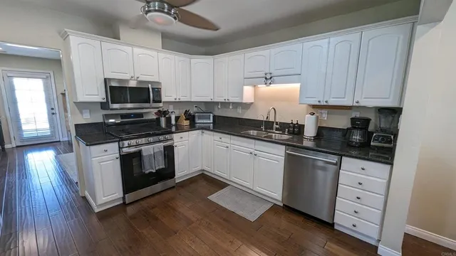 a kitchen with granite countertop a sink cabinets and stainless steel appliances