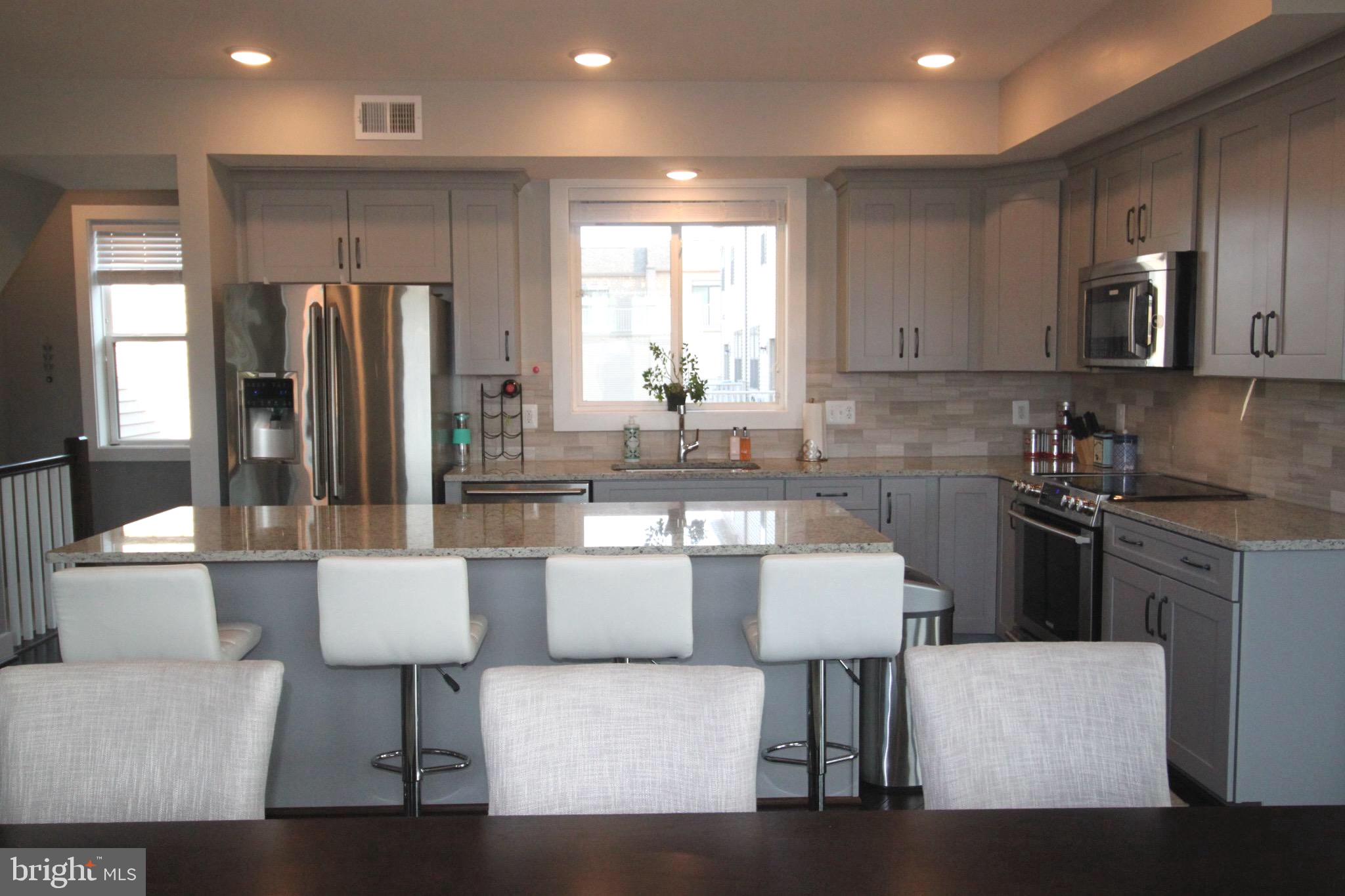 44738 Tiverton Square Ashburn, VA 20147 - Photo 6 of 66 a kitchen with stainless steel appliances granite countertop a refrigerator a stove a sink a dining table and chairs with wooden floor
