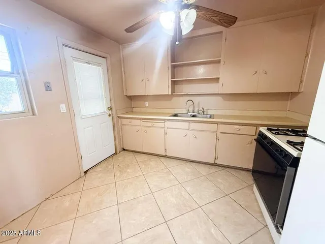 a kitchen with a sink a stove cabinets and a window