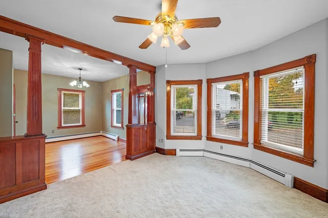 an empty room with chandelier fan and windows