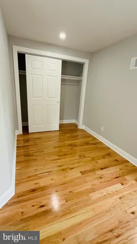 a view of an empty room with wooden floor and window