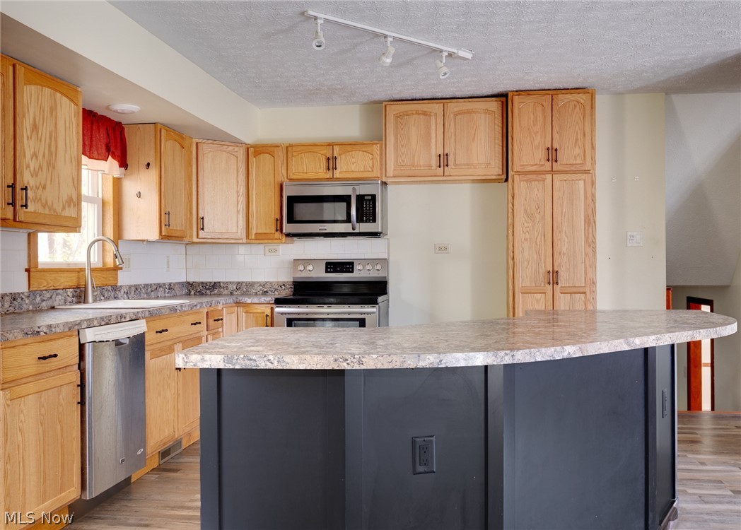 9416 Kieffer Road Mantua, OH 44255 - Photo 12 of 29 Kitchen featuring tasteful backsplash, light brown cabinets, appliances with stainless steel finishes, light countertops, and a textured ceiling
