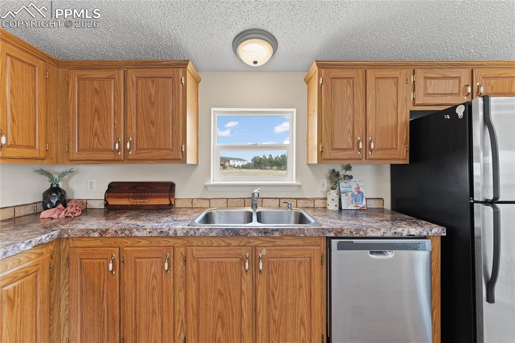 5505 Whipshaw Road Peyton, CO 80831 - Photo 13 of 39 a kitchen with granite countertop stainless steel appliances a refrigerator sink and cabinets