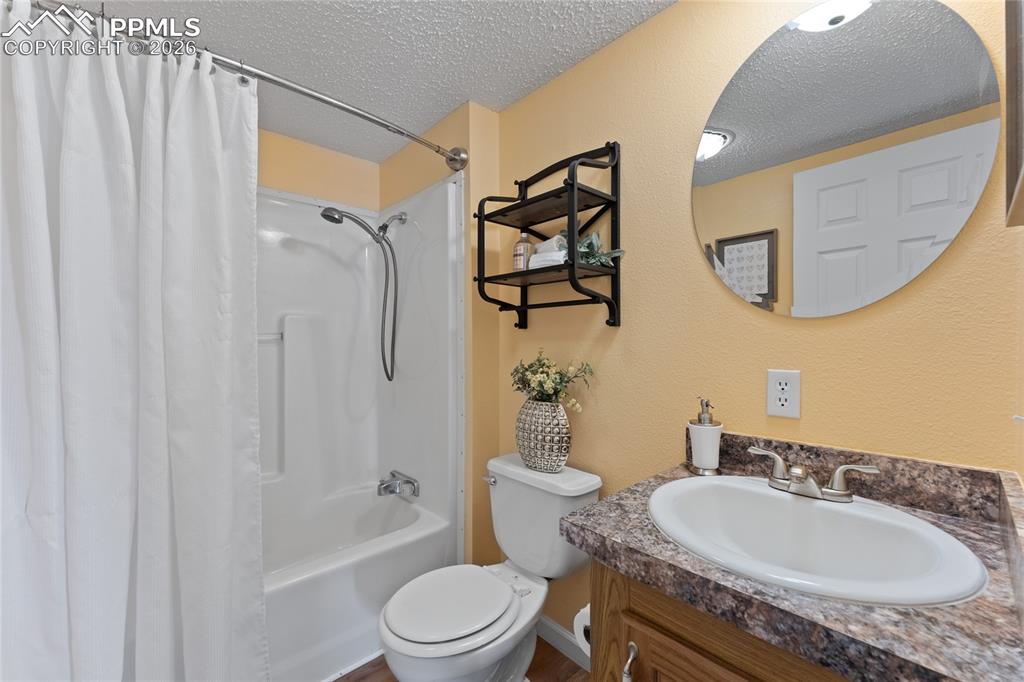 5505 Whipshaw Road Peyton, CO 80831 - Photo 30 of 39 a bathroom with a granite countertop sink mirror vanity and a toilet