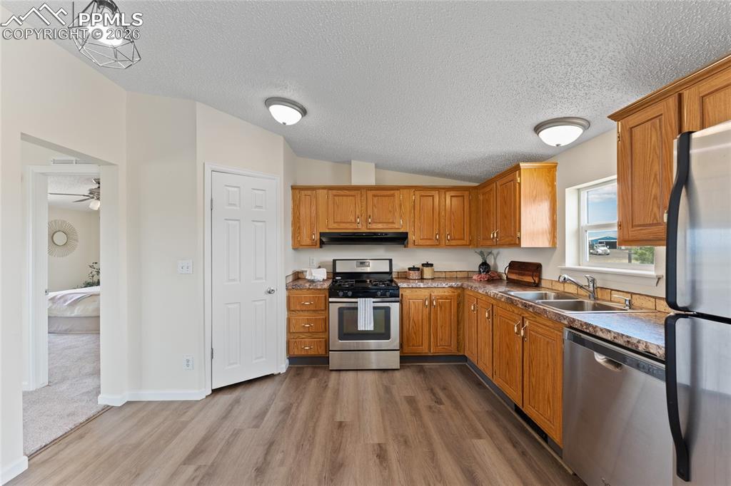 5505 Whipshaw Road Peyton, CO 80831 - Photo 10 of 39 a kitchen with stainless steel appliances granite countertop hardwood floor sink stove and wooden cabinets