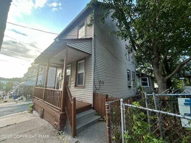 a view of a house with a fence and a tree