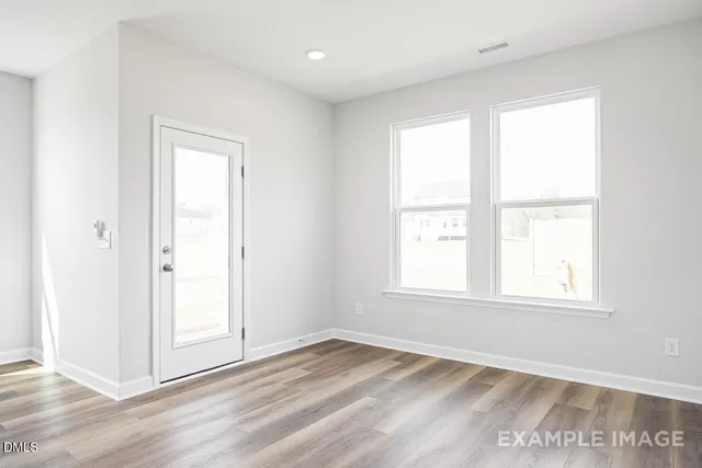an empty room with wooden floor fan and windows