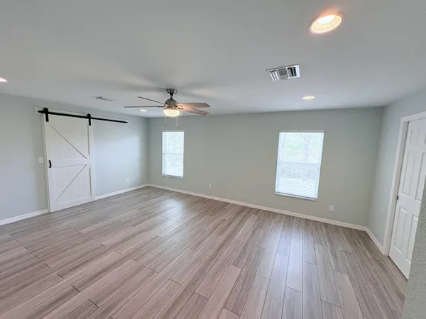 an empty room with wooden floor and windows