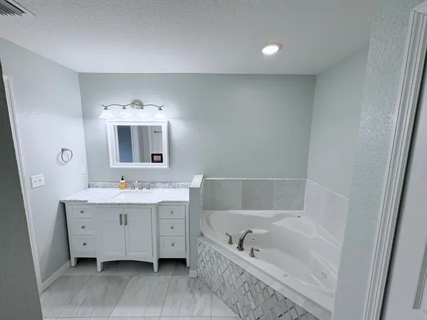 a bathroom with a tub sink and mirror