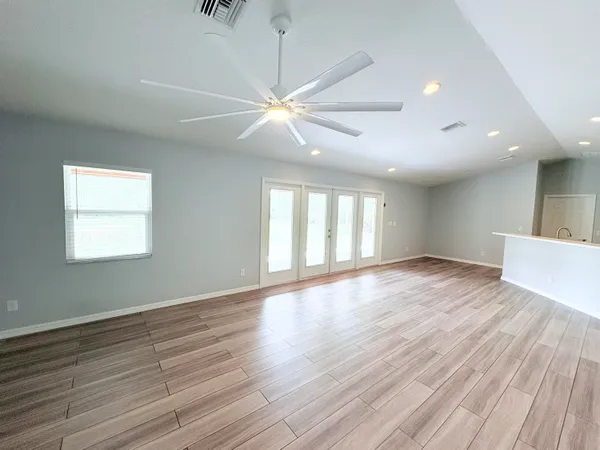 a view of an empty room with wooden floor and a window