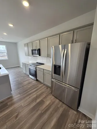 a kitchen with stainless steel appliances a refrigerator sink and wooden floor