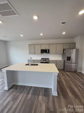 a large kitchen with kitchen island a large counter top space a sink stainless steel appliances and cabinets