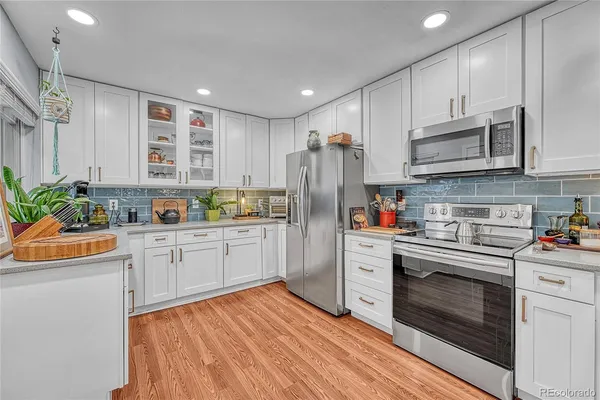 a kitchen with stainless steel appliances granite countertop a refrigerator a stove and a sink with wooden floor