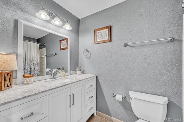 a bathroom with a granite countertop toilet sink and mirror