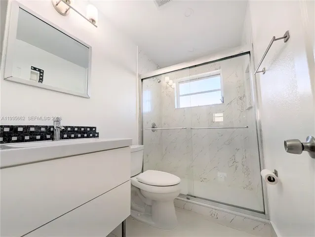 a bathroom with a granite countertop sink a toilet and shower