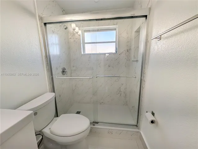 a white toilet sitting next to a shower