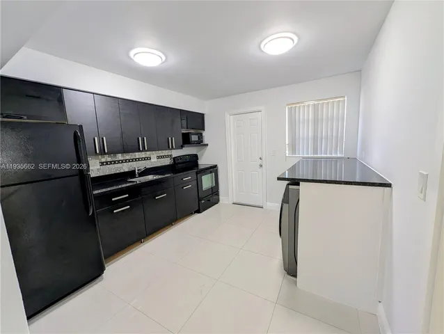 a kitchen with kitchen island a counter top space a sink stainless steel appliances and cabinets