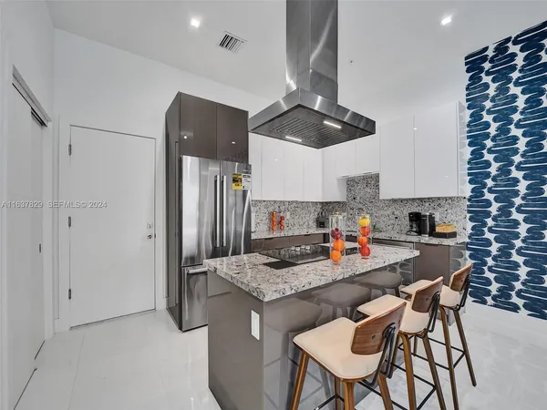 a kitchen with stainless steel appliances kitchen island granite countertop a dining table chairs and white cabinets