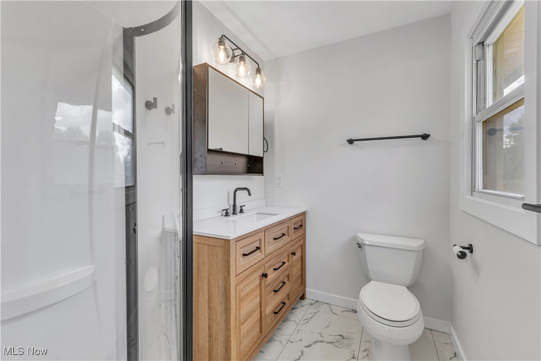 7843 Stone Road Medina, OH 44256 - Photo 18 of 27 Bathroom with marble look tiles, toilet, vanity, baseboards, and a shower stall