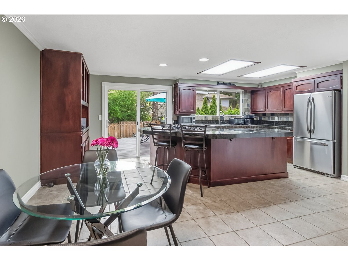 5660 Southwest Glenbrook Road Beaverton, OR 97007 - Photo 18 of 41 a kitchen with stainless steel appliances granite countertop a refrigerator a sink dishwasher a dining table and chairs with wooden floor
