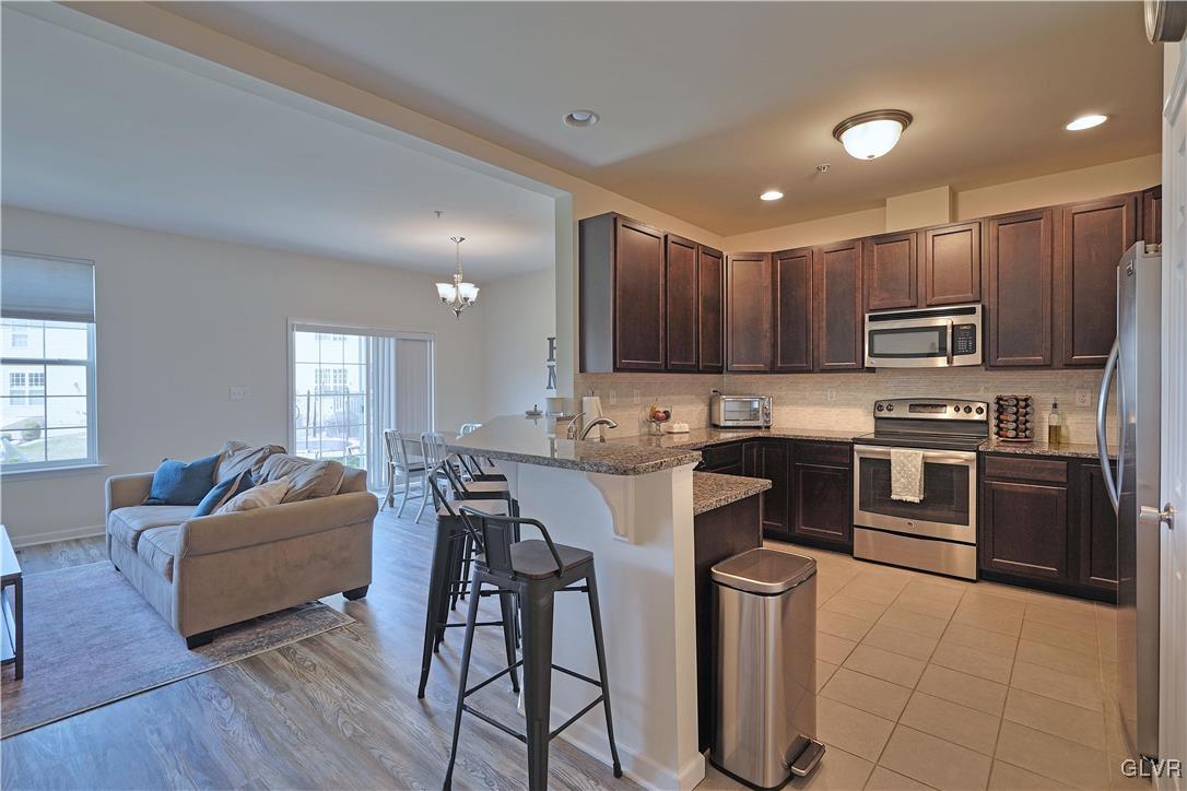 229 Snapdragon Way Allentown, PA 18104 - Photo 4 of 27 a kitchen with kitchen island granite countertop wooden floors and stainless steel appliances