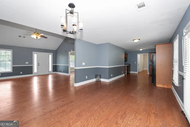 a kitchen with stainless steel appliances granite countertop a refrigerator a sink dishwasher a stove and white countertops with wooden floor