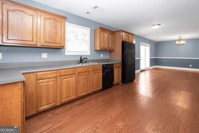 an empty room with wooden floor chandelier fan and windows